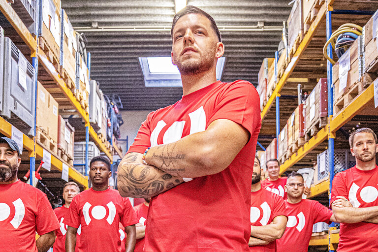 Groupe de collègues BELFOR en tenue de travail faisant preuve d'esprit d'équipe dans un hall.